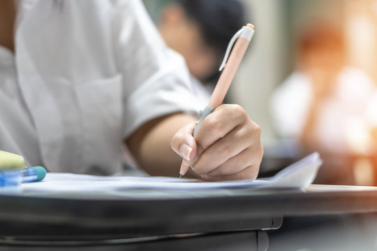Exam at school with student's taking educational admission test in class, thinking hard, writing answer in university classroom, education and world literacy day concept