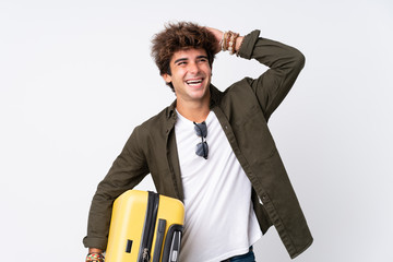 Young Traveler man holding a suitcase over isolated white background laughing