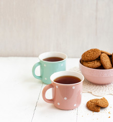 A tasty snack: two cups of tea and a bowl of cookies...