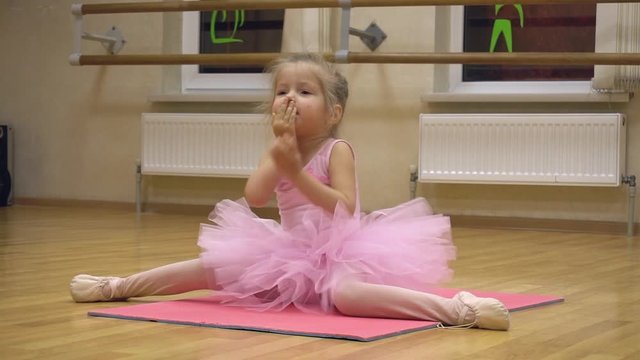Little ballerina in pink dress doing choreography practice
