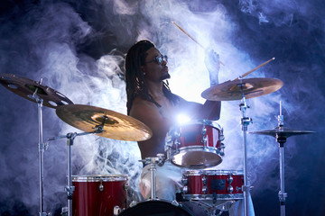 african young naked handsome man hitting on drums, perussion instruments isolated over smoky...