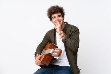 Young caucasian man with guitar over isolated white background doing silence gesture