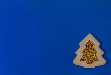 Christmas card wooden tree and multi-colored balls on a blue background. Flat lay, copy space, top view. New Year. Greeting card.