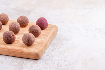 Homemade Raw Vegan Cacao Energy Balls on Wooden Tray on White Marble Background. Healthy Chocolate Candy from Nuts and Dates. Concept of Natural Vegetarian Handmade Dessert. Copy Space