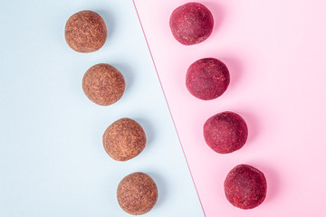 Homemade Raw Vegan Cacao Energy Balls Lie in Row on Trend Blue and Pink Paper Background. Healthy Chocolate Snacks from Nuts and Dates. Concept of Natural Vegetarian Handmade Dessert