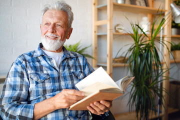 Senior man at home reading book and enjoying retirement, penison