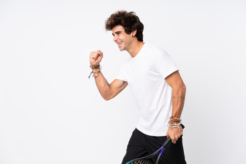 Young caucasian man over isolated white background playing tennis and celebrating a victory