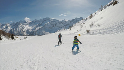 Little boy skiing in the Alpine resort..A 6 year old child enjoys a winter holiday with his mother. .