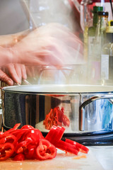 Stockholm, Sweden A steaming pot and a frying pan on the stove with red peppers to be mixed in.