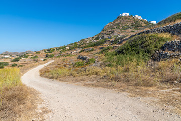 Dirty road with rocks and vegetation and Plaka village