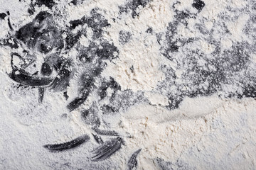 Flour spilling on black background. View from above. The concept of baking and pastry.