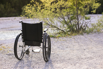 Empty wheelchair standing in a park on walking path
