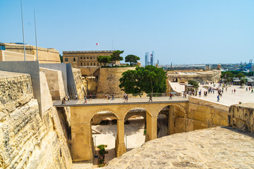 The bridge going over the Ditch to the City Gate of Valletta, Malta. In the background is Saint James Bastion and the Central Bank of Malta. - obrazy, fototapety, plakaty