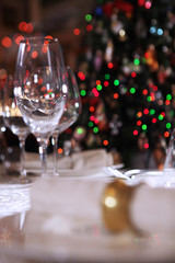Empty champagne glasses on the table. The Christmas tree and the napkin on the plate are out of focus.