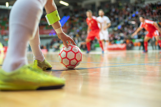 Futsal match - close up of ball in the corner and player's hand and legs.