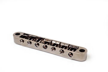 Metallic guitar bridge, suitable for electric and acoustic guitars, disassembled, closeup shot on a white background