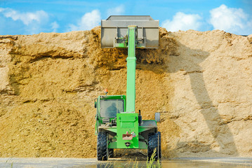 Front loader in front of a maize chaff depot
