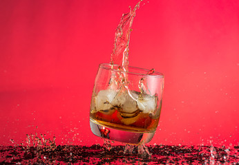 falling glass of whiskey with ice in motion frozen with a spray and splash