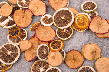 Fototapeta na wymiar Dried lemon, orange and apple slices on a grey structured background