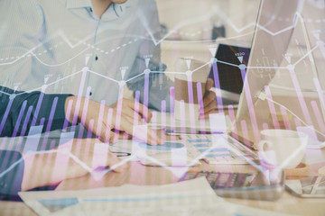 Multi exposure of chart with man typing on computer in office on background. Concept of hard work.