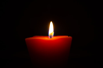 Closeup of burning candle isolated on black background