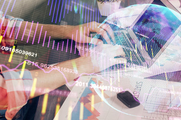 Double exposure of stock graph with businessman typing on computer in office on background. Concept of hard work.