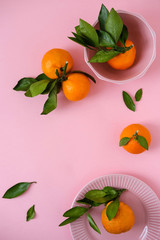 Tangerines in pink bowl on pink background. Top view. Flat lay. Copy Space.