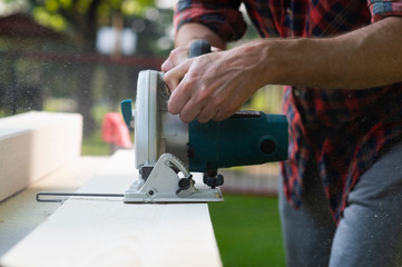 Carpenter using circular saw cutting wooden boards