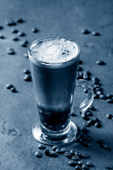Fizzy iced Coffee espresso with milk,roasted beans around over grey green texture background. Modern drink. Color of the year 2020 classic blue toned