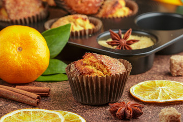 Fresh baked homemade citrus (orange, Mandarin) cakes muffins with brown sugar, cinnamon and star anise in black teflon baking dish over on wooden table. Selective focus