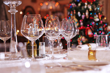 Table setting for the holiday New year or Christmas. Christmas tree out of focus. Empty glass wine glasses.
