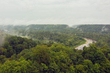 Aerial view on the river Gauja and National park Gauja with pine forest  from the main big tower of medieval Turaida Castle in cloudy, foggy and rainy day, Sigulda, Latvia. Soft focus