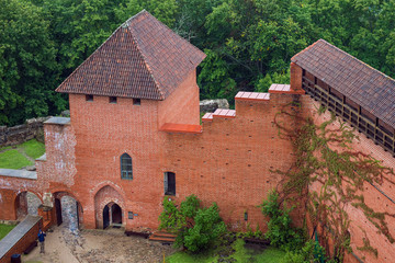 Aerial view on the courtyard and red brick buildings of medieval Turaida Castle from the main big tower in cloudy, foggy and rainy day, Sigulda, Latvia. Soft focus.