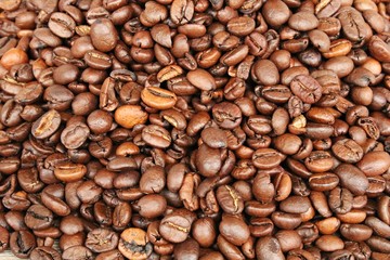 Lots of roasted coffee beans in a large pot prepared for grinding