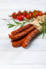 Thin Dry Smoked Polish Sausage Kabanos or Cabanossi on White Wooden Background. Selective focus.