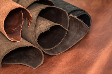 Rolls of natural brown and black leather. Materials for leather craft