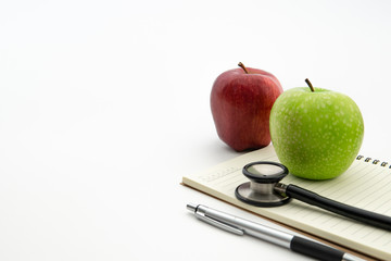 green and red apple with stethoscope on notepad with white background