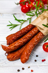 Thin Dry Smoked Polish Sausage Kabanos or Cabanossi on White Wooden Background. Selective focus.