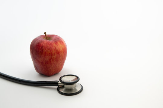 red  apple with stethoscope in isolated white background. healthy diet concept