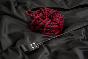 Stack for BDSM games and shibari rope on black silk background