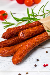 Thin Dry Smoked Polish Sausage Kabanos or Cabanossi on White Wooden Background. Selective focus.
