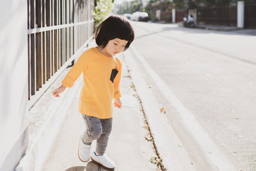Portrait of adorable young Asian toddler walking explore morning sun nearby the house, having healthy morning walk can absorb vitamin D, healthy lifestyle, healthy child, with copy space to the right.