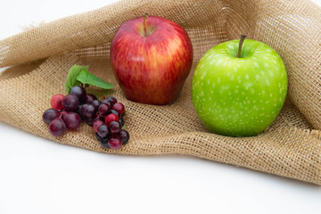 Organic fruits with red apple, green apple and grapes on sackcloth in isolate background. Daily healthy diet concept 