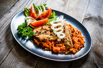 Fish dish - fried fish fillet on vegetable sauce on wooden table