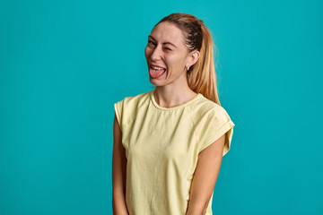 Fototapeta premium Beautiful portrait of a young girl on a blue background. Young emotional smile and surprised, angry woman screaming.