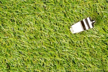 Soccer sports chrome whistle on grass background - penalty, foul or sports concept, top view flat...