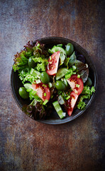 Salad with green Olives, Tomatoes and Cucumber on rustic Background. Healthy Snack Idea. Top view. 