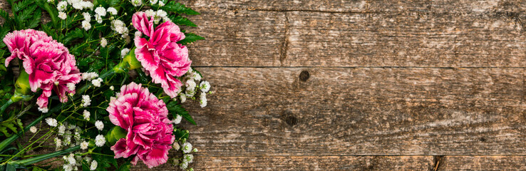 Fototapeta premium Top view of Carnation Flowers on White Vintage Wooden Background. Design concept for mothers day, wedding and valentines day with copy space. Selective focus.