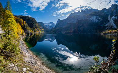 Naklejka na ściany i meble Autumn Alps mountain lake with clouds reflections. Gosauseen or Vorderer Gosausee lake, Upper Austria. Dachstein summit and glacier in far.