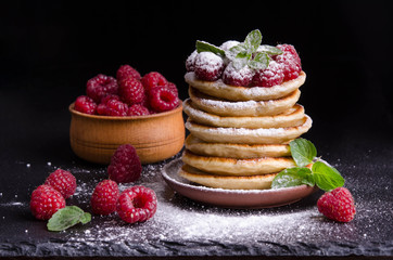 Pancakes with raspberries and berries around on black backgound